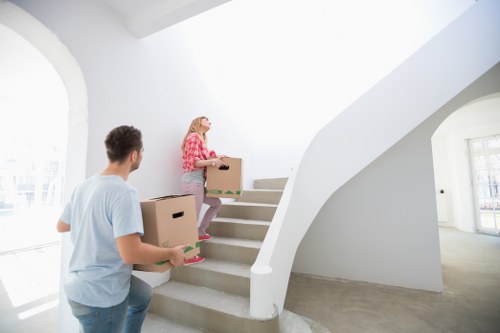 Removal team carrying boxes through a stairwell during flat removals in Ruislip
